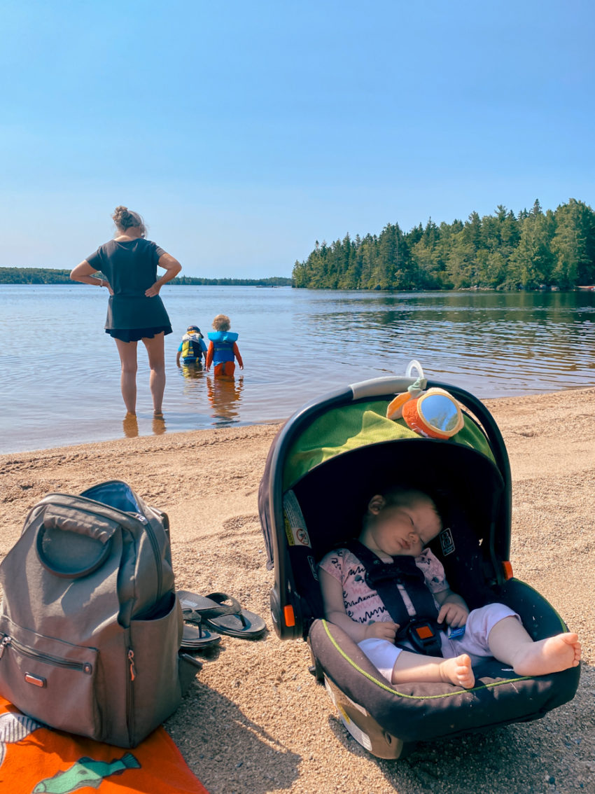 a baby sleeps in her car seat at aylesford lake beach